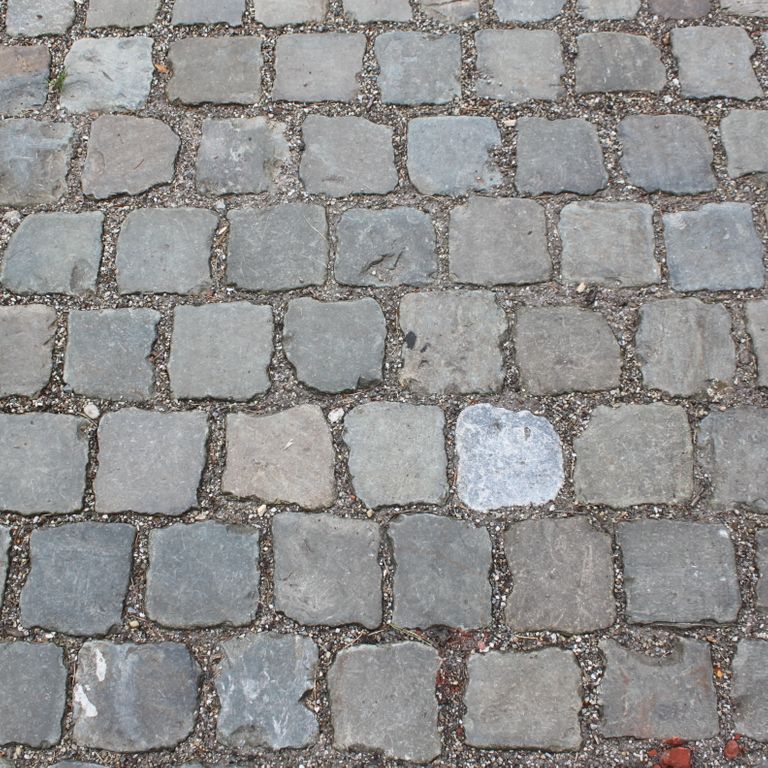 Application image for Reclaimed European Porphyry Cobblestones - Worn Cubes. The image shows this product being used in a path pavers application. The surface finish shown is . The dominant color shown is gray. The color mix creates a warm feeling.