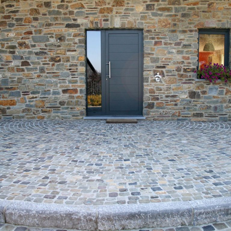 Application image for Reclaimed European Sandstone Cobblestones - Worn Cubes. The image shows this product being used in a patio pavers application. The surface finish shown is . The dominant color shown is gray. The color mix creates a warm feeling.
