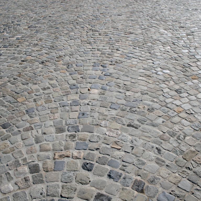 Application image for Reclaimed European Sandstone Cobblestones - Worn Cubes. The image shows this product being used in a driveway pavers application. The surface finish shown is . The dominant color shown is gray. The color mix creates a cool feeling.
