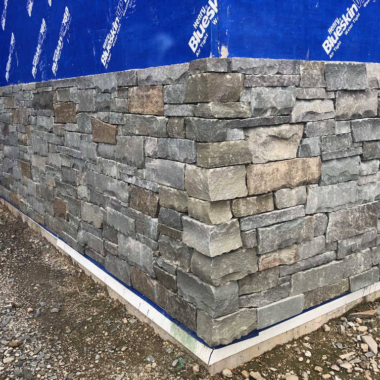 Application image for Colonial Wall Granite - Veneer. The image shows this product being used for full bed veneer and thin veneer. The surface finish shown is split-face. The dominant color shown is gray; with beige, brown, orange/rust, purple, white and tan secondaries. The color mix creates a warm feeling. Regular color pattern.