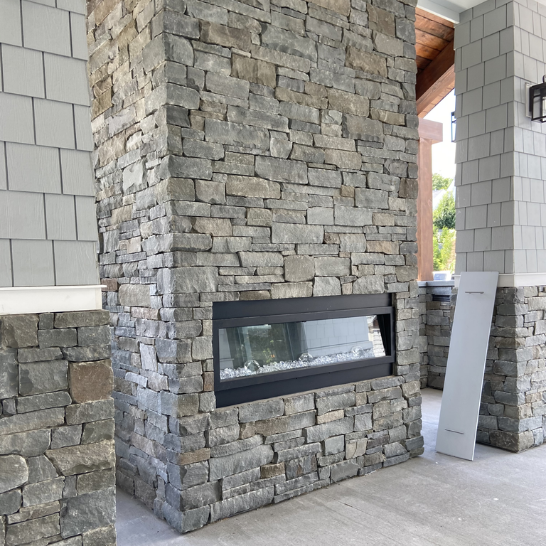 Application image for Colonial Wall Granite - Veneer. The image shows this product being used for full bed veneer and thin veneer. The surface finish shown is split-face. The dominant color shown is gray; with beige, blue, brown and purple secondaries. The color mix creates a warm feeling. Regular color pattern.