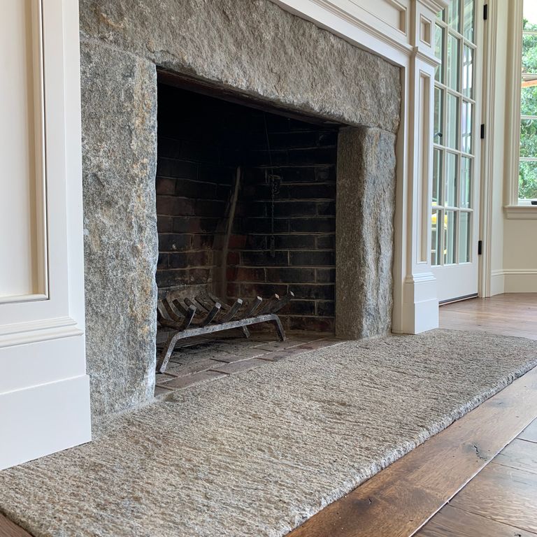 Feature image for Reclaimed Granite Bridge Blocks - Fireplace Hearth. The image shows this product being used in a fireplace hearth application. The dominant color shown is gray; with beige, green, purple, white and tan secondaries. Exhibits 