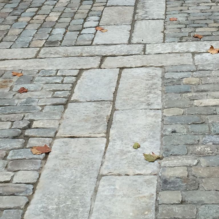 Close-up image for Reclaimed Granite Curbstone - Junior Banding and Inlays. The surface finishes shown are split-face, weathered and worn. Dominant colors shown are gray and white; with a beige secondary. Exhibits 
