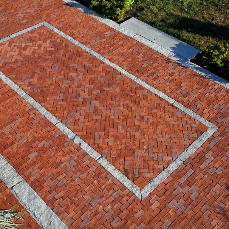 Feature image for Reclaimed Granite Curbstone - Junior Banding and Inlays. The image shows this product being used in a patio pavers application. The dominant color shown is gray; with a white secondary. The color mix creates a cool feeling. Speckled and blotched color patterns.