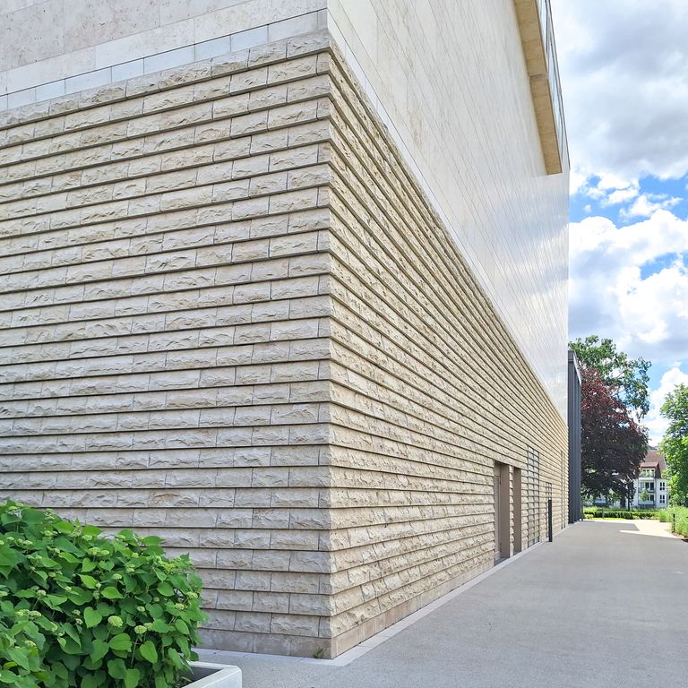 Application image for Bavarian Beige Limestone - Veneer. The image shows this product being used in a full bed veneer application. The surface finish shown is split-face. Dominant colors shown are beige, tan and cream. The color mix creates a warm feeling.