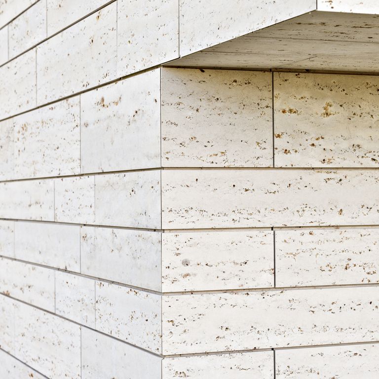 Close-up image for Bavarian Travertine - Beige - Wall Veneer. The surface finish shown is sand blasted. Dominant colors shown are white and cream; with beige and brown secondaries. Regular and coarse speckled color patterns. Contains mineral inclusions.