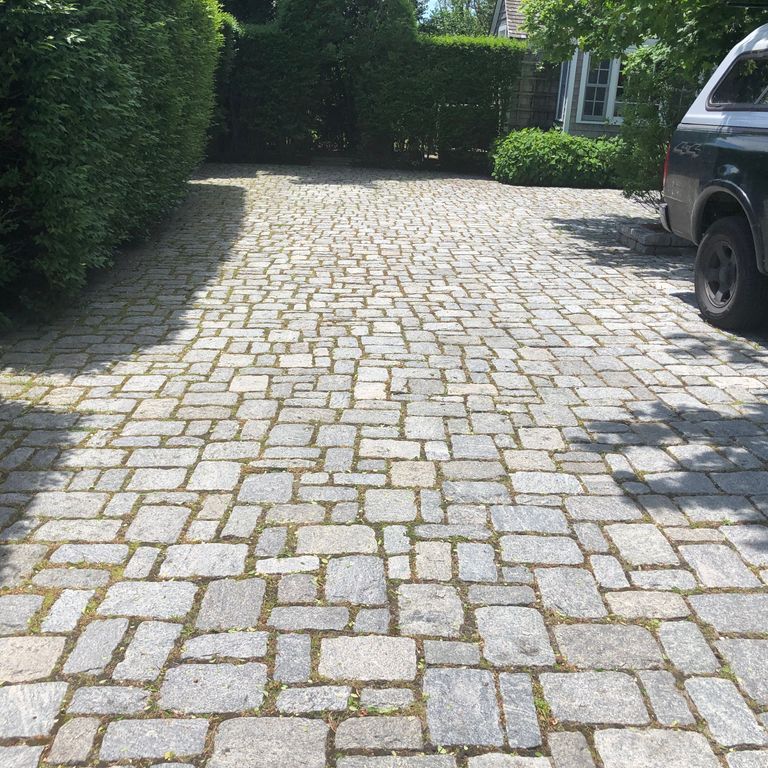 Application image for Gray Granite Cobblestone - Rectangles. The image shows this product being used in a driveway pavers application. The surface finish shown is tumbled. The dominant color shown is gray; with beige and cream secondaries. Exhibits 