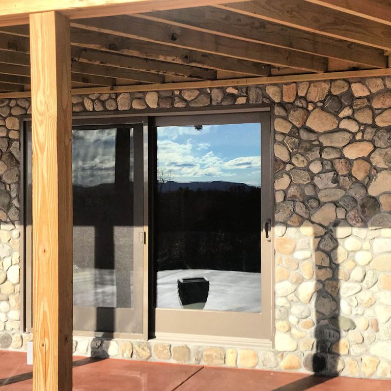 Application image for Newport River Rounds - Thin Veneer. The image shows this product being used for landscape wallstone and thin veneer. The surface finish shown is natural. Dominant colors shown are brown, tan and cream; with beige and orange/rust secondaries. The color mix creates a warm feeling.