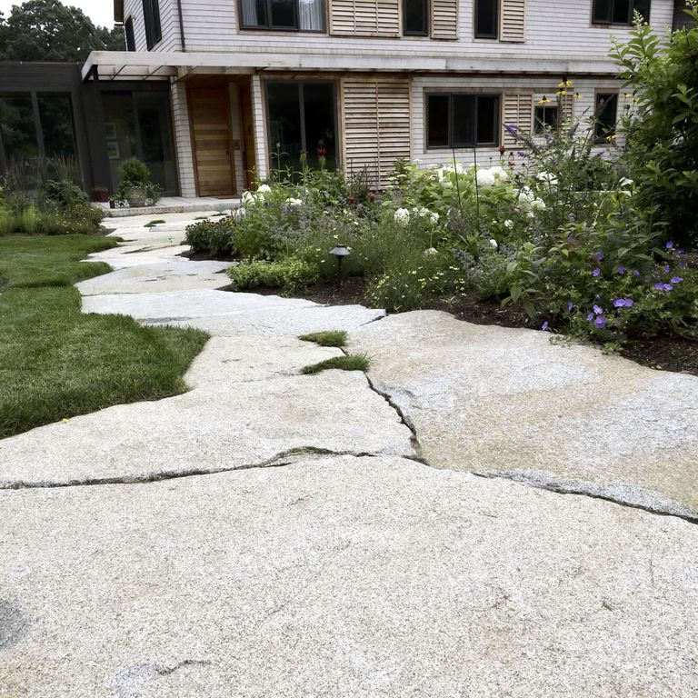 Application image for Dodlin Hill Granite - Irregular Pavers. The image shows this product being used in a path pavers application. The surface finish shown is natural cleft. Dominant colors shown are black and gray. The color mix creates a warm feeling.