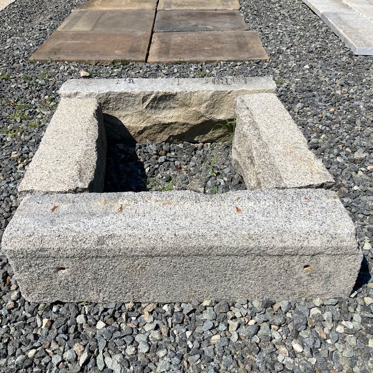 Application image for Reclaimed Granite Curbstone Fire Feature. The image shows this product being used in an outdoor fire concepts application. The surface finish shown is a combination of weathered and worn. The dominant color shown is gray; with beige, white and cream secondaries. The color mix creates a warm feeling. Speckled color pattern.