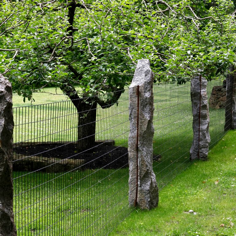 Application image for Reclaimed First Generation Curbstone - Posts. The image shows this product being used in a posts application. The surface finish shown is . The dominant color shown is gray; with black, brown and white secondaries. The color mix creates a cool feeling. Speckled and blotched color patterns. Contains lots of mica and mineral inclusions.