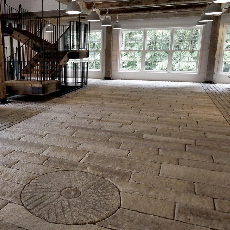 Feature image for Reclaimed First Generation Granite Curbstone - Gauged Floor Planks. The image shows this product being used in an interior floor application. Dominant colors shown are brown and gray; with black, blue, purple and tan secondaries. The color mix creates a warm feeling. Regular and blotched color patterns.
