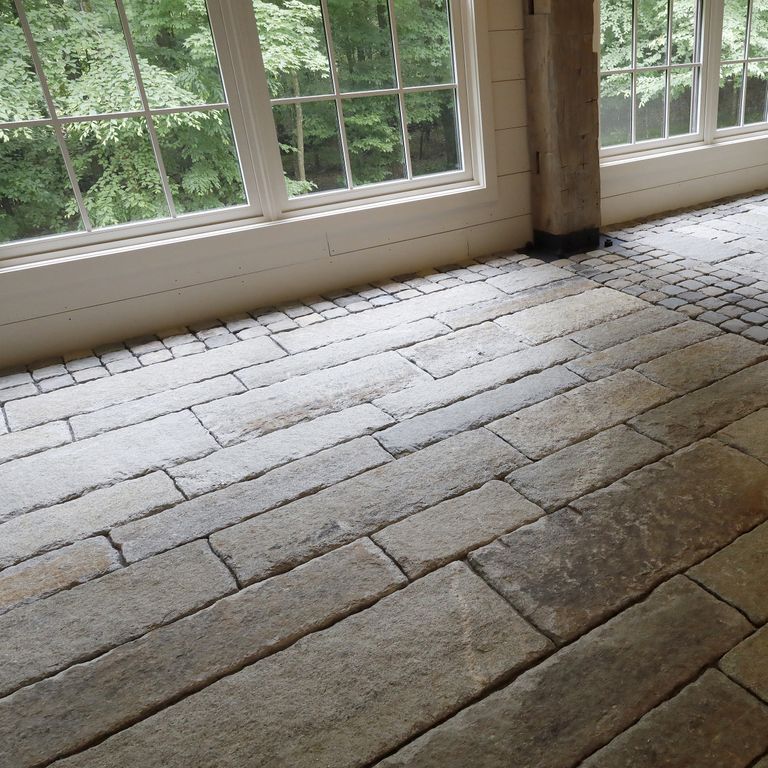 Application image for Reclaimed First Generation Granite Curbstone - Gauged Floor Planks. The image shows this product being used in an interior floor application. The surface finish shown is a combination of split-face with flat plane, weathered and worn. Dominant colors shown are brown and gray; with black, purple, white and tan secondaries. The color mix creates a warm feeling. Regular and blotched color patterns.