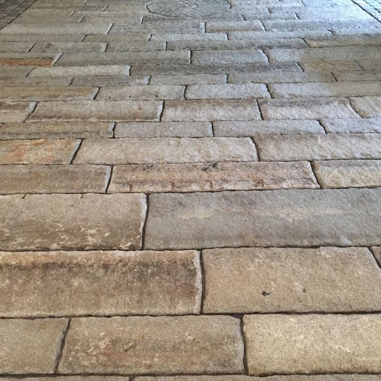 Application image for Reclaimed First Generation Granite Curbstone - Gauged Floor Planks. The image shows this product being used in a patio pavers application. Dominant colors shown are brown, gray and tan. The color mix creates a cool feeling.