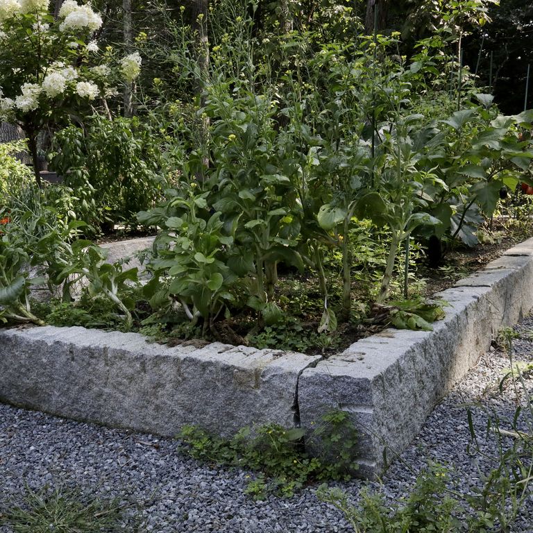 Application image for Reclaimed Granite Curbstone Garden Accents. The image shows this product being used in a garden accents application. The surface finish shown is a combination of chiseled, split-face, weathered and worn. The dominant color shown is gray; with blue and brown secondaries. The color mix creates a warm feeling. Speckled color pattern.
