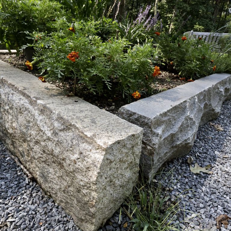 Application image for Reclaimed Granite Curbstone Garden Accents. The image shows this product being used in a garden accents application. The dominant color shown is gray; with beige, blue, brown and purple secondaries. The color mix creates a warm feeling. Speckled color pattern.