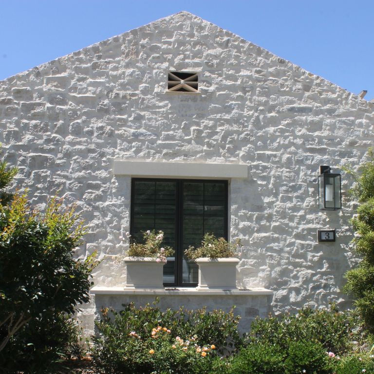 Application image for Tundra Cream Limestone - Veneer. The image shows this product being used for full bed veneer and thin veneer. The surface finish shown is split-face. Dominant colors shown are white, tan and cream; with blue and pink secondaries. The color mix creates a cool feeling.