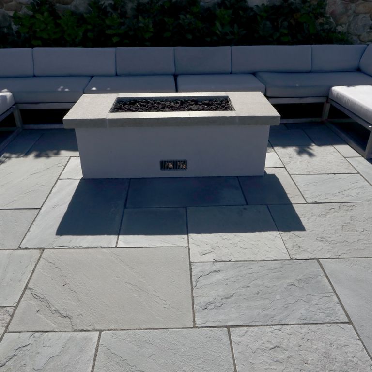 Application image for Bluestone Flamed Surface Blue/Gray Fire Feature. The image shows this product being used in an outdoor fire concepts application. The surface finish shown is flamed. The dominant color shown is gray. The color mix creates a cool feeling. Solid color pattern.