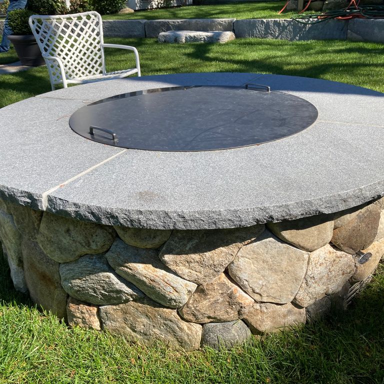 Application image for Bluestone Flamed Surface Blue/Gray Fire Feature. The image shows this product being used in an outdoor fire concepts application. The surface finish shown is flamed. The dominant color shown is gray. The color mix creates a cool feeling. Solid color pattern.