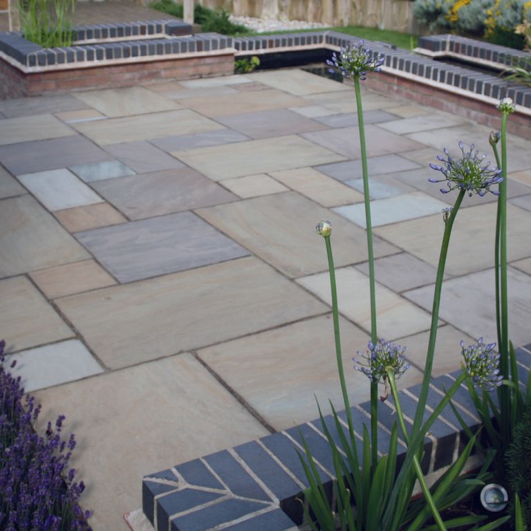 Best close-up image for Lakeland Sandstone - Pavers. The image shows this product being used in a patio pavers application. The surface finish shown is natural cleft. Dominant colors shown are blue and gray; with white and tan secondaries. The color mix creates a warm feeling. Regular and linear color patterns.