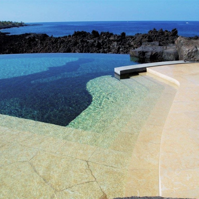 Best close-up image for Cenia Beige Limestone Pool Deck Pavers. The image shows this product being used for pool coping and pool deck pavers. The surface finish shown is flamed. Dominant colors shown are beige and tan; with orange/rust, white and cream secondaries. Exhibits 