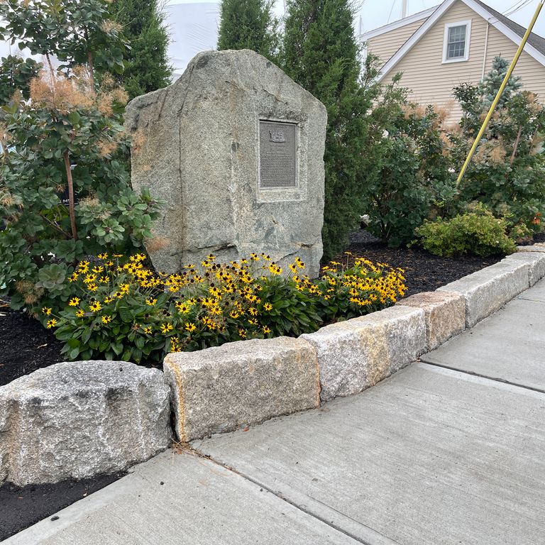 Application image for Reclaimed Granite Block - Edging. The image shows this material being used in a landscape curbing & edging application. The surface finish shown is a combination of weathered and worn. The dominant color shown is gray; with a brown secondary.