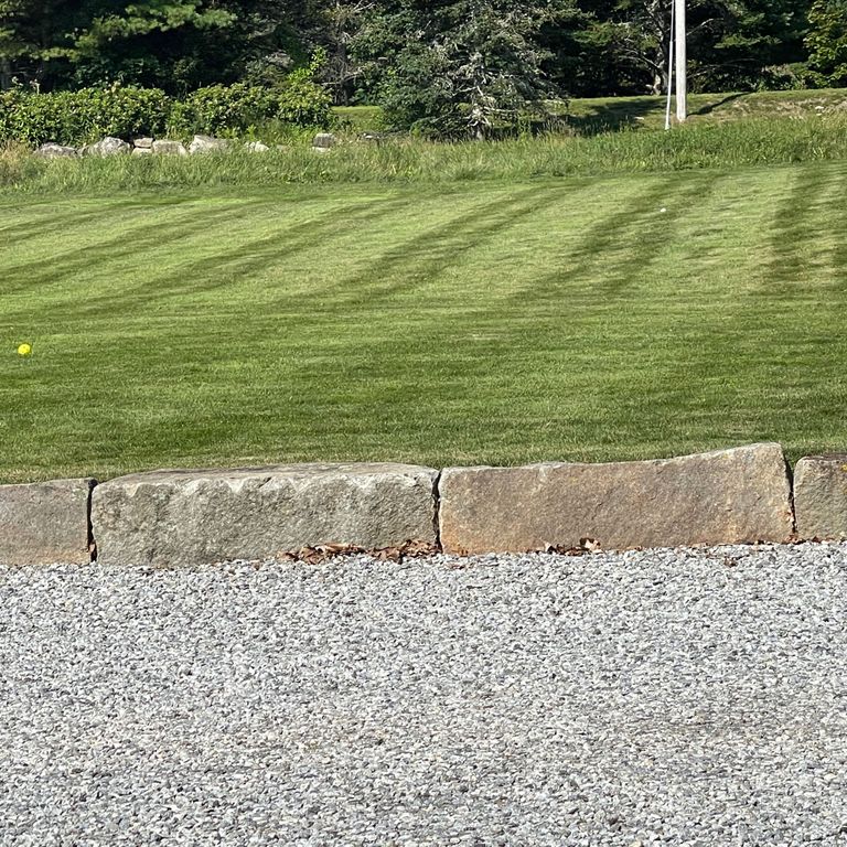 Application image for Reclaimed Granite Block - Edging. The image shows this product being used in a landscape curbing & edging application. The surface finish shown is a combination of split-face and weathered. Dominant colors shown are brown and tan; with gray and orange/rust secondaries. The color mix creates a warm feeling.