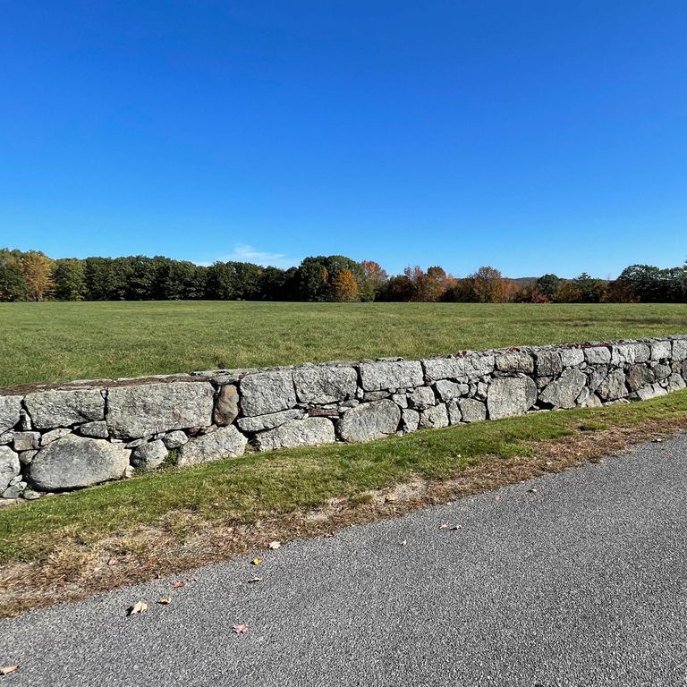 Application image for New England Fieldstone Mix - Oversized Wallstone. The image shows this product being used in a landscape wallstone application. The surface finish shown is weathered. The dominant color shown is gray; with beige and white secondaries. The color mix creates a cool feeling.