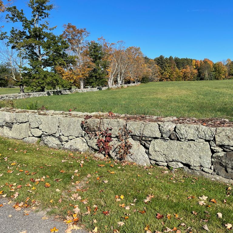 Application image for New England Fieldstone Mix - Oversized Wallstone. The image shows this product being used in a landscape wallstone application. The surface finish shown is weathered. Dominant colors shown are beige and tan; with gray, white and cream secondaries.