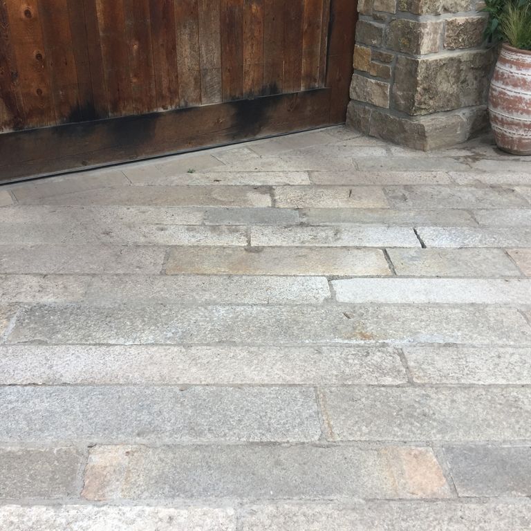 Feature image for Reclaimed Footworn Granite Plank Pavers - Gauged. The image shows this product being used in a patio pavers application. The design pattern shown is planks with varied heights and lengths. The dominant color shown is gray; with beige, pink, purple, white, tan and cream secondaries. Exhibits 