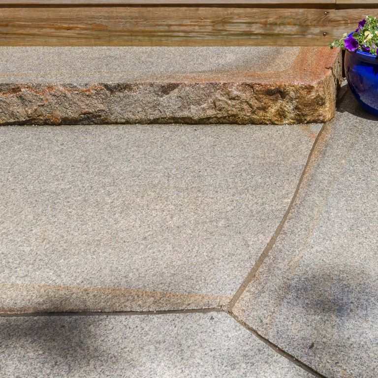 Application image for Cape Neddick Full Color Granite - Flamed Top Live Edge Steps. The image shows this product being used in a monolithic steps application. Dominant colors shown are beige and gray; with brown, orange/rust and white secondaries. Exhibits 