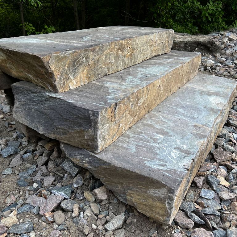 Application image for Granite - Mystic Mountain - Live Edge Steps - Flamed Tops. The image shows this product being used in a monolithic steps application. The surface finish shown is a combination of flamed and natural. The dominant color shown is gray; with beige, blue, brown, orange/rust, white, tan and cream secondaries. Exhibits 