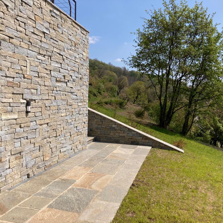 Application image for Pietra Italia Full Color Gneiss - Pavers. The image shows this product being used in a patio pavers application. The surface finish shown is natural cleft. Dominant colors shown are beige and tan; with brown, gray, orange/rust, pink and cream secondaries. The color mix creates a warm feeling. Contains some mica and mineral inclusions.