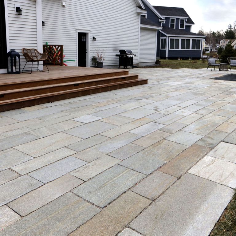 Application image for Pietra Italia Full Color Gneiss - Pavers. The image shows this product being used for patio pavers and pool deck pavers. The surface finish shown is natural cleft. Dominant colors shown are beige and gray. The color mix creates a warm feeling. Regular and streaked color patterns. Contains some mica and mineral inclusions.