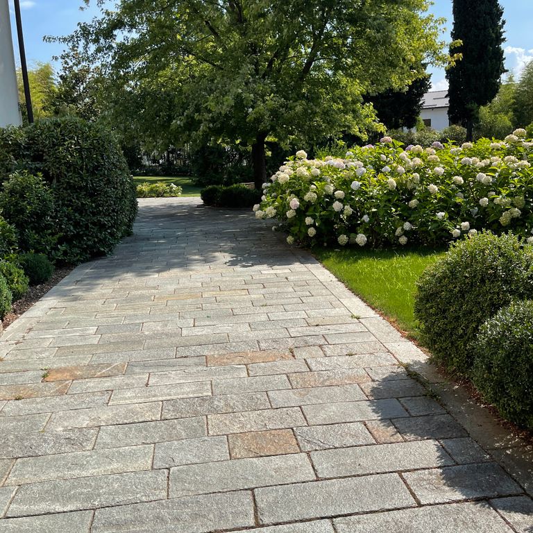Application image for Pietra Italia Full Color Gneiss - Pavers. The image shows this product being used in a path pavers application. The surface finish shown is natural cleft. Dominant colors shown are beige and gray. Fine speckled and random color patterns.