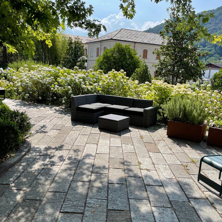 Application image for Pietra Italia Full Color Gneiss - Pavers. The image shows this product being used in a patio pavers application. The surface finish shown is natural cleft. Dominant colors shown are beige and gray. The color mix creates a warm feeling. Regular color pattern.