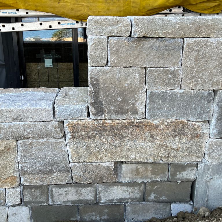 Application image for Reclaimed Granite Curbstone - Full Bed Veneer. The image shows this product being used for wallstone cap and full bed veneer. The surface finish shown is . Dominant colors shown are gray and tan. Exhibits 