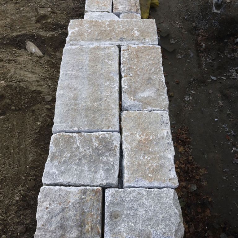 Application image for Reclaimed Granite Curbstone - Full Bed Veneer. The image shows this product being used for wallstone cap and full bed veneer. The surface finish shown is . Dominant colors shown are gray and tan. Exhibits 
