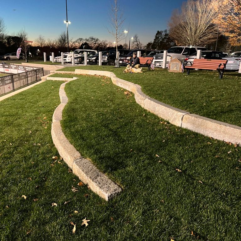 Feature image for Reclaimed Granite Curbstone - Radius Curve. The image shows this product being used in a landscape curbing & edging application. The surface finish shown is a combination of ,  and . Dominant colors shown are gray and tan. The color mix creates a warm feeling.