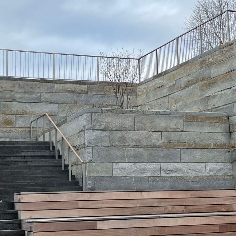 Application image for Reclaimed Granite Curbstone - Plank Veneer. The image shows this product being used in a full bed veneer application. The surface finish shown is . Dominant colors shown are gray and tan. The color mix creates a warm feeling. Regular and random color patterns.