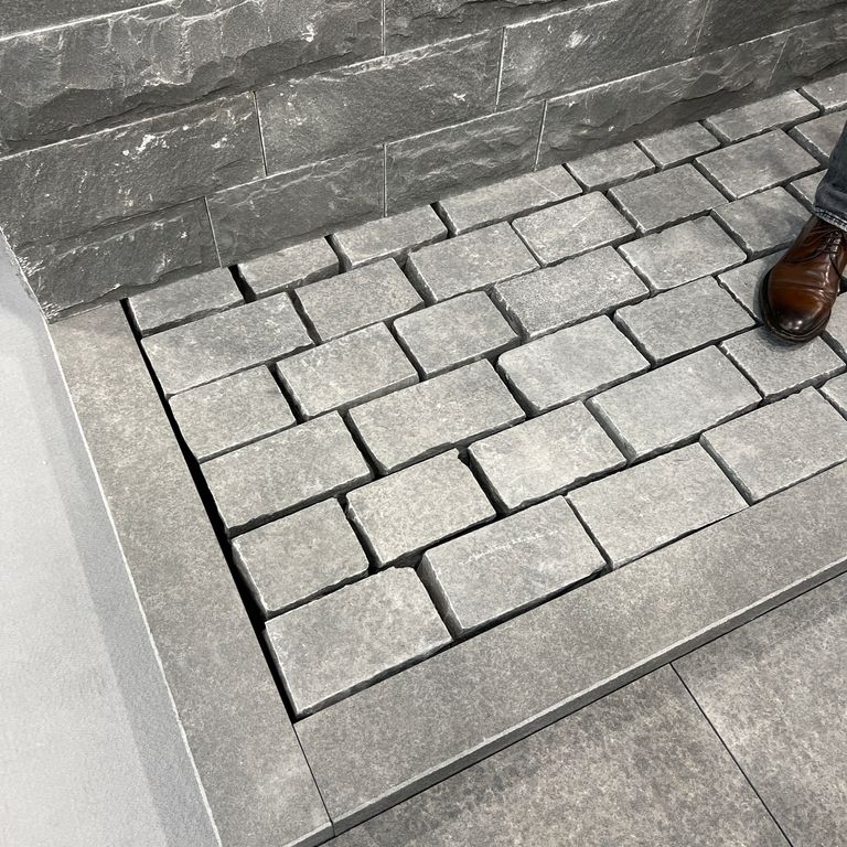 Feature image for Polar Gray Limestone Cobblestones. The image shows this product being used in a path pavers application. The surface finish shown is flamed. The dominant color shown is gray. The color mix creates a cool feeling. Regular color pattern.