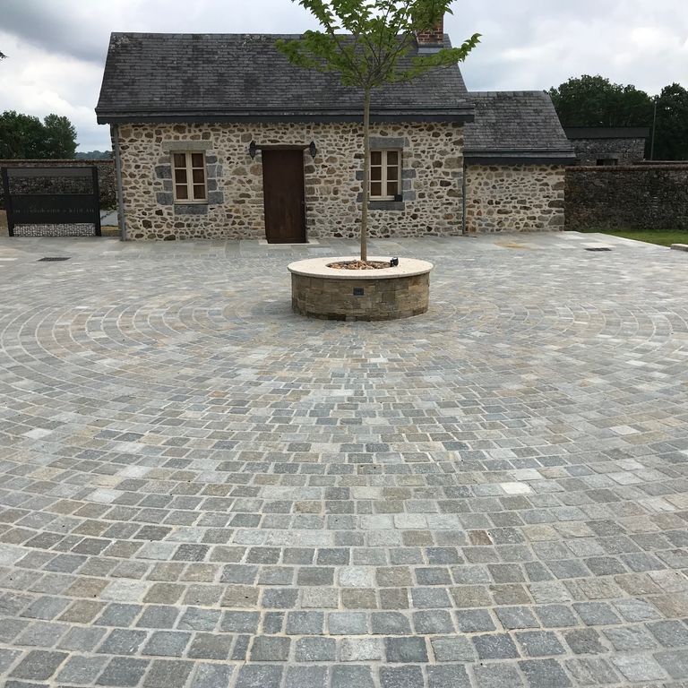 Application image for Pietra Italia Full Color Gneiss - Cobblestone Cubes. The image shows this product being used for patio pavers and public area. The surface finish shown is split-face. Dominant colors shown are beige and gray. The color mix creates a warm feeling.
