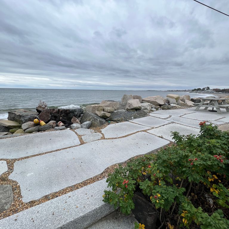 Feature image for Granite - Chelmsford Gray - Live Edge Paver. The image shows this product being used in a patio pavers application. Dominant colors shown are blue and gray.