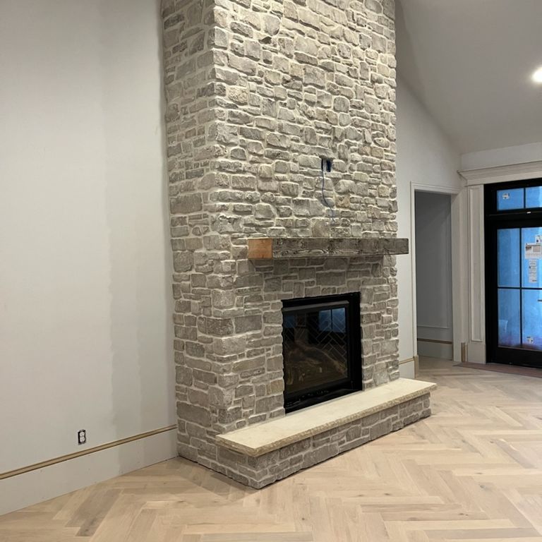 Application image for Lannon Gray Limestone Veneer - Splitface + Tumbled. The image shows this product being used for fireplace surround and thin veneer. Dominant colors shown are beige, gray and tan. The color mix creates a warm feeling.