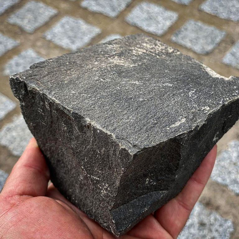 Application image for Basalt - Black Moon - Cobblestone. The image shows this product being used in a patio pavers application. The surface finish shown is split-face. The dominant color shown is gray.