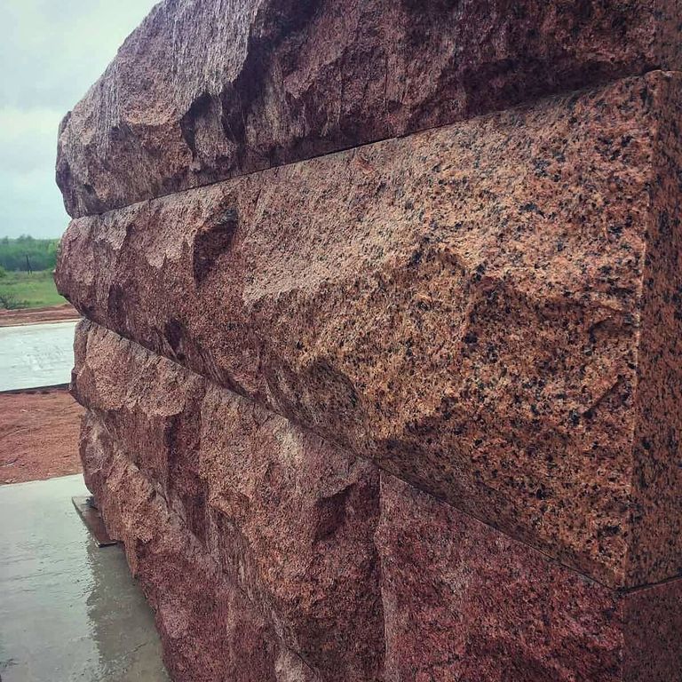 Application image for Granite - Red Pomegranate - Veneer. The image shows this product being used in a landscape wallstone application. The surface finish shown is split-face. The dominant color shown is red. The color mix creates a warm feeling.