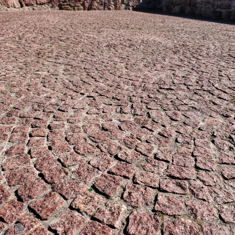Application image for Granite - Red Pomegranate - Cobblestone. The image shows this product being used in a patio pavers application. The surface finish shown is split-face. Dominant colors shown are orange/rust and red. The color mix creates a warm feeling.