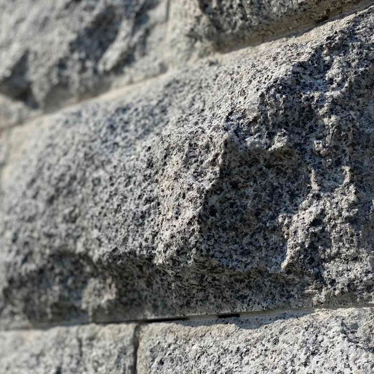 Application image for Granite - White House - Veneer. The image shows this product being used in a thin veneer application. The surface finish shown is split-face. Dominant colors shown are gray and white. The color mix creates a cool feeling.