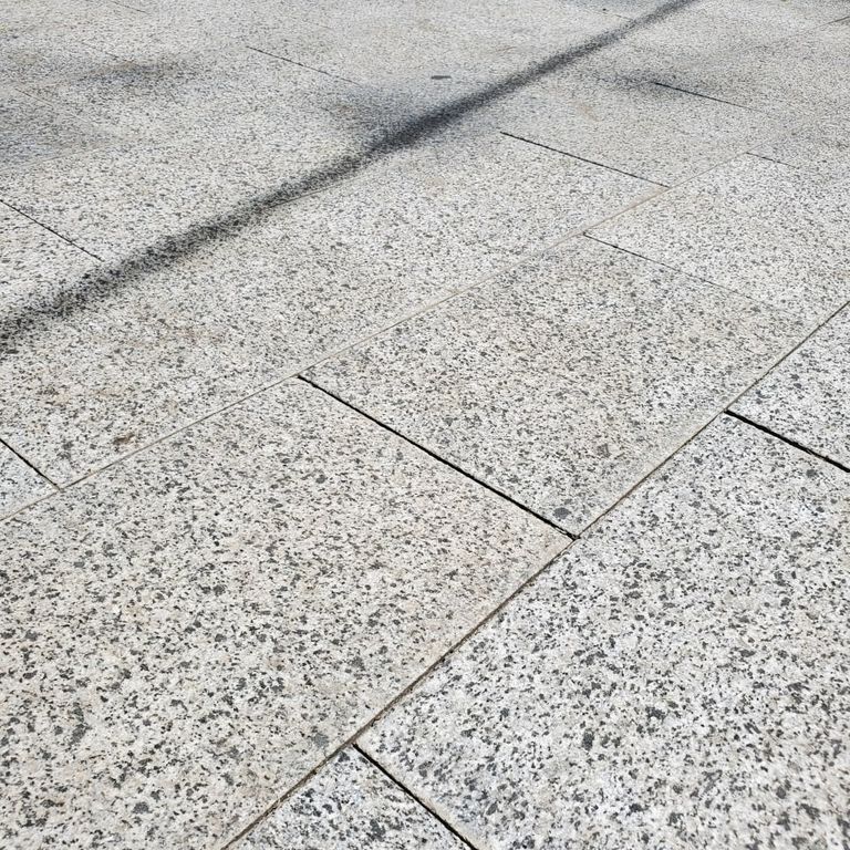 Application image for Granite - White House - Pavers. The image shows this product being used in a patio pavers application. The surface finish shown is flamed. Dominant colors shown are gray and white. The color mix creates a cool feeling.