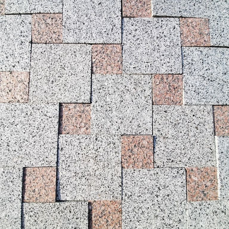 Application image for White House Granite - Pavers. The image shows this product being used in a patio pavers application. The surface finish shown is flamed. Dominant colors shown are gray and white. The color mix creates a cool feeling.